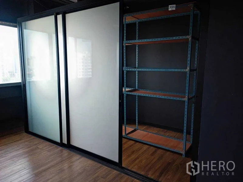 Office Space for rent in Watthana, Bangkok - Frosted glass sliding doors beside tall windows and metal rack storage.