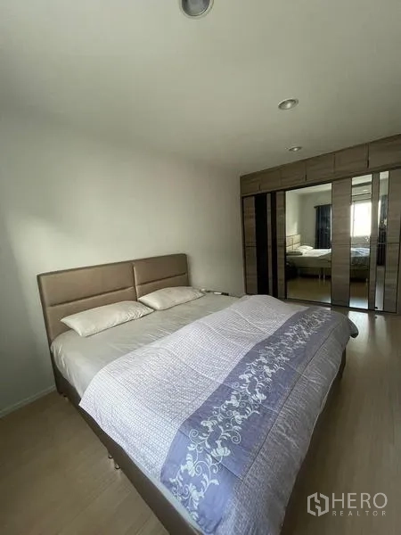 Townhouse for rent in Suan Luang, Bangkok - Bedroom featuring an upholstered bed and mirrored wardrobe on wood floors.