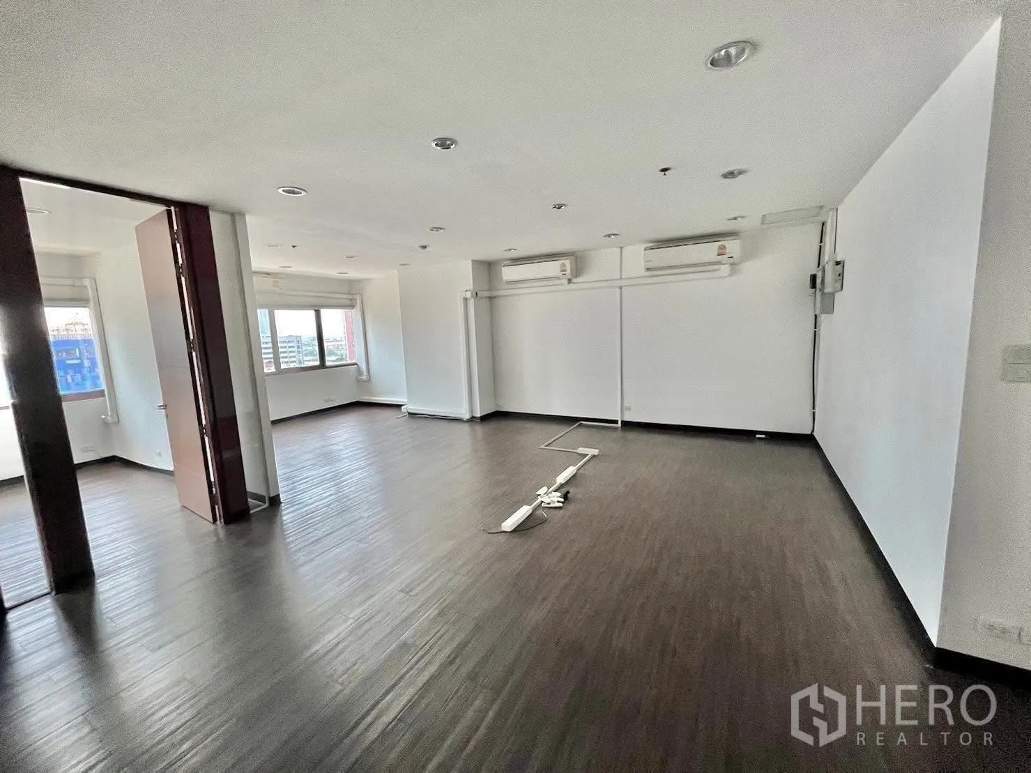 Office Space for rent in Watthana, Bangkok - Open-plan office with dark wood flooring, recessed downlights and wide windows.
