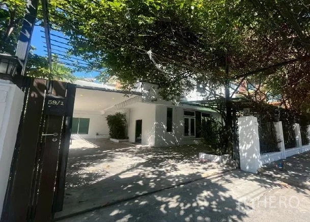 Home Office for rent in Watthana, Bangkok - Gated entrance with vine-covered canopy opening to a private driveway and parking area.