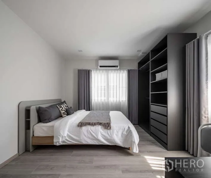 Detached House for rent or sale in Bang Phli, Samut Prakan - Bedroom with bed, air conditioner and large open shelving wardrobe in a dark finish.
