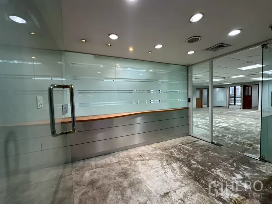 Office Space for rent in Khlong Toei, Bangkok - Glass-walled reception with frosted panels and downlights leading into an open-plan office.