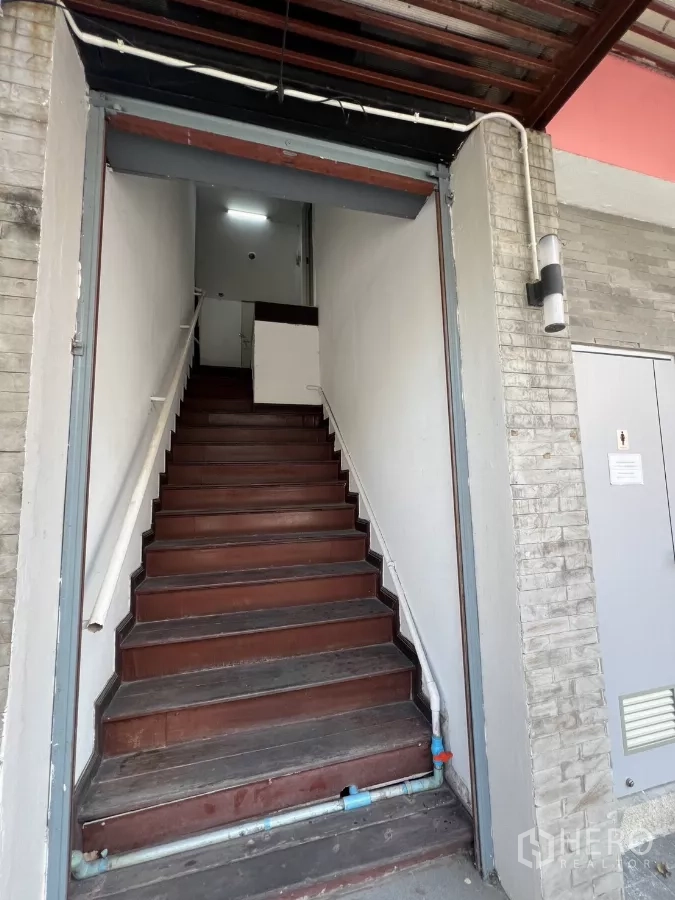 Retail Space for rent - External staircase entrance with wooden steps and white walls.