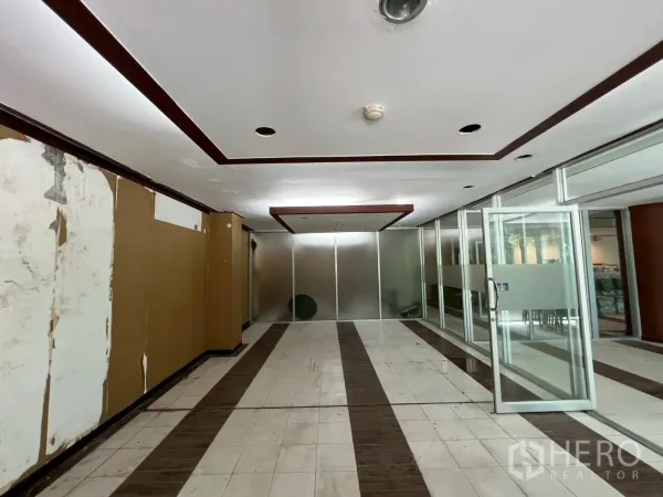 零售空间 出租 - 走廊区域，嵌入式照明，磨砂玻璃办公室与瓷砖地面，适合翻新升级。