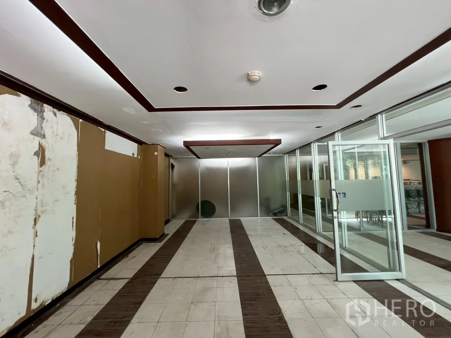 零售空间 出租 - 走廊区域，嵌入式照明，磨砂玻璃办公室与瓷砖地面，适合翻新升级。