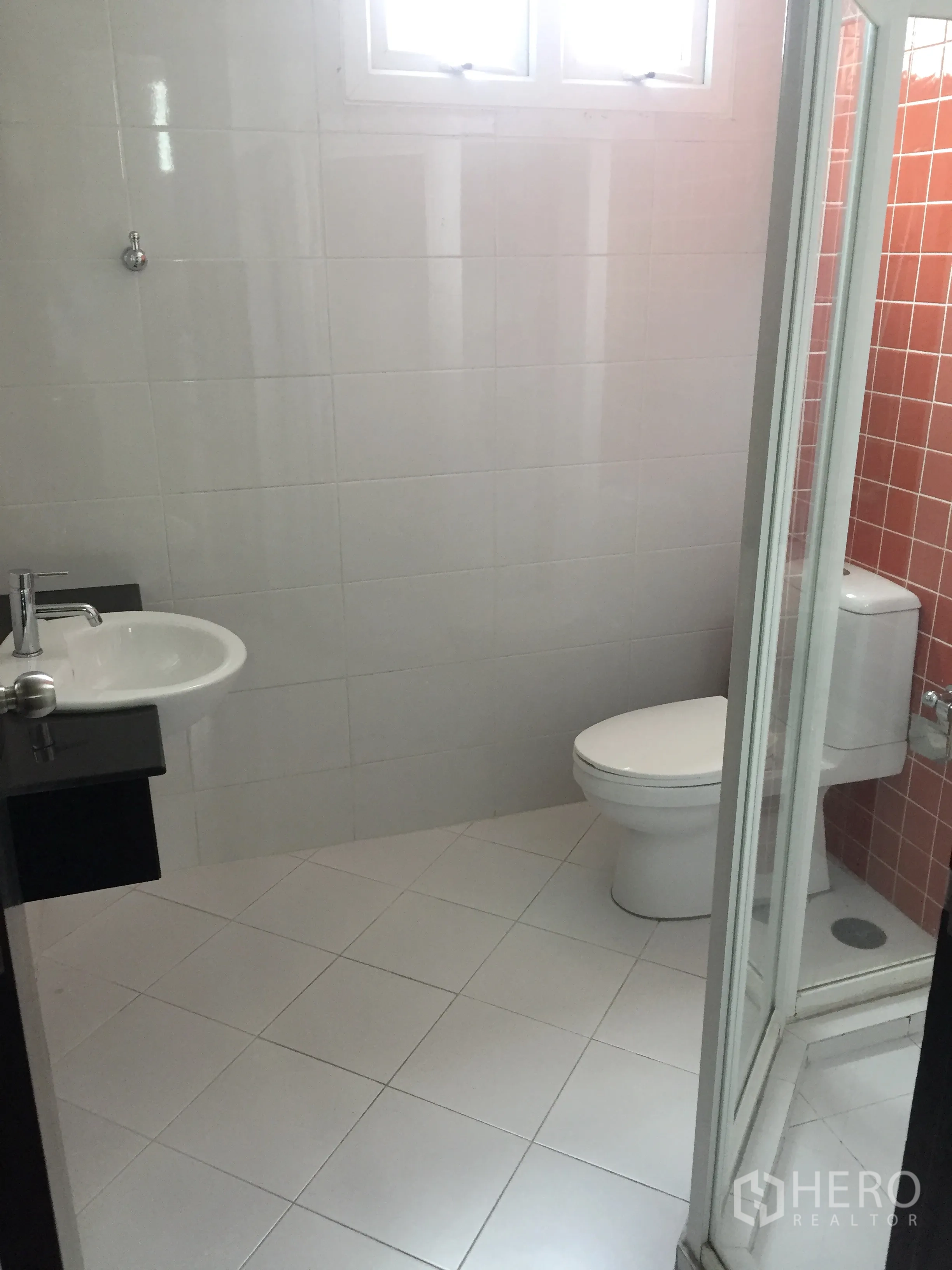 Condominium for rent in Khlong Toei, Bangkok - Clean bathroom with a glass shower enclosure, white tiles and a small window.