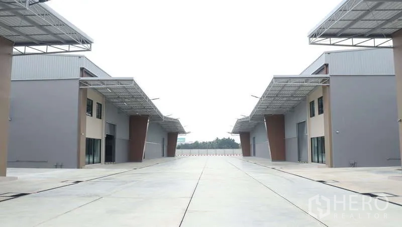 Warehouse for rent in Sam Phran, Nakhon Pathom - Wide concrete driveway between warehouse buildings designed for truck maneuvering.