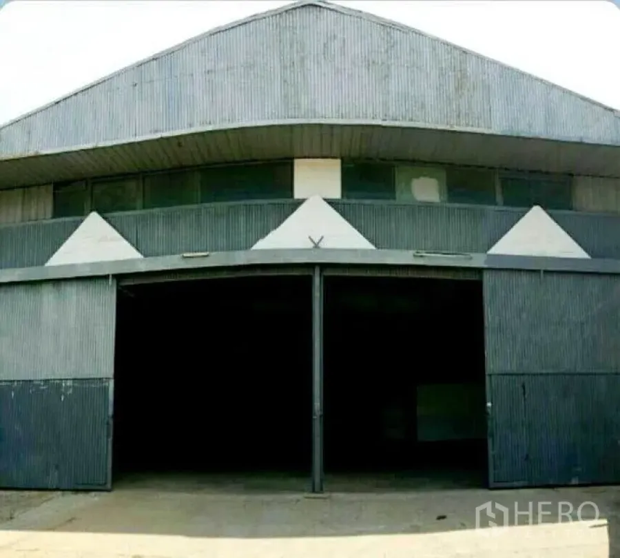 Warehouse for rent in Sai Mai, Bangkok - Front elevation of gabled warehouse with twin sliding metal doors and driveway.