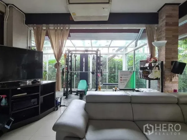 Detached House for sale in Bang Na, Bangkok - Open living area facing a glass-enclosed home gym with garden views.