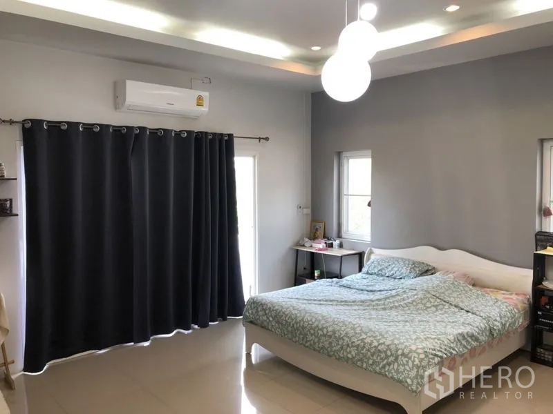 Detached House for sale in Lam Luk Ka, Pathum Thani - Bedroom with large bed, air conditioner and blackout curtains.