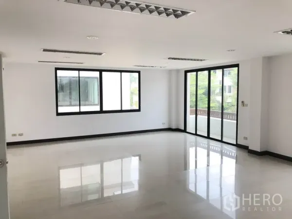 Home Office for rent in Wang Thonglang, Bangkok - Bright open-plan office floor with white tiles, recessed lights and sliding glass doors to a balcony.