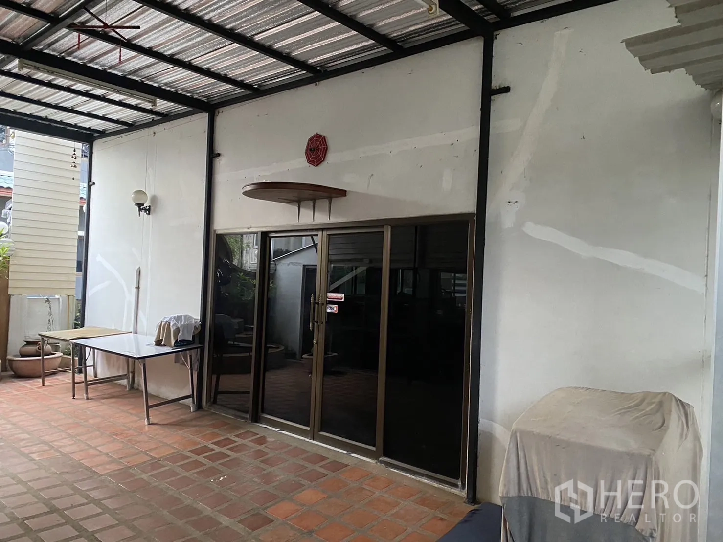 Factory for rent in Prawet, Bangkok - Covered terrace with sliding glass doors and terracotta tile flooring at the factory entrance.