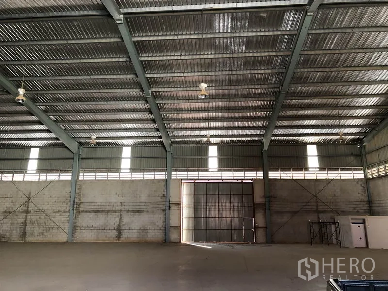 Warehouse for rent in Sai Noi, Nonthaburi - Interior facing the large loading door with ventilated metal walls, high-bay lights and wide open floor space.