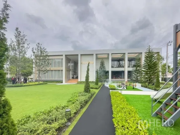 Townhouse for rent in Suan Luang, Bangkok - Community clubhouse surrounded by manicured lawns, pathway, and landscaped gardens.