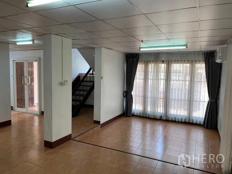 Office Space for rent in Chatuchak, Bangkok - Open-plan office with tiled floors, glass entry, staircase and full-height curtained windows.