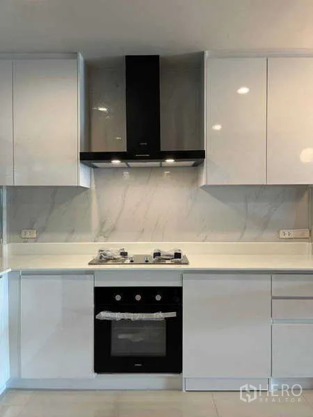 Townhouse for rent in Khlong Toei, Bangkok - Close-up of sleek white cabinetry, gas cooktop, and built-in oven with range hood.