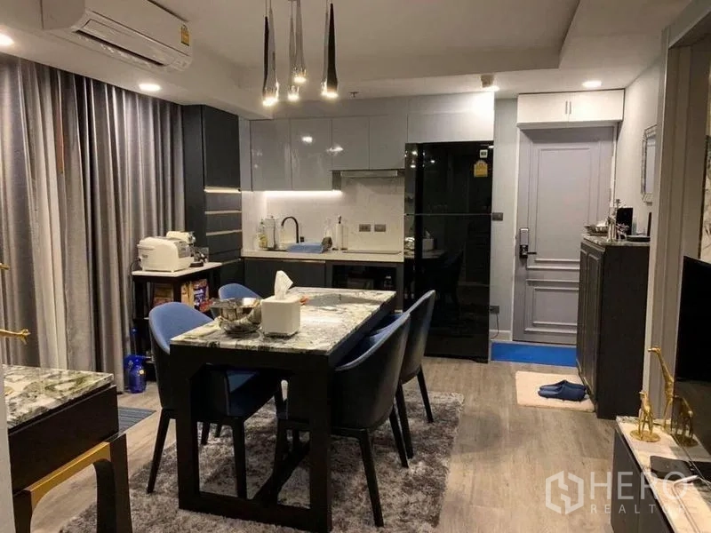 Condominium for sale in Khlong Toei, Bangkok - Open-plan kitchen and dining with glossy cabinetry, black fridge, marble dining table and pendant lighting.