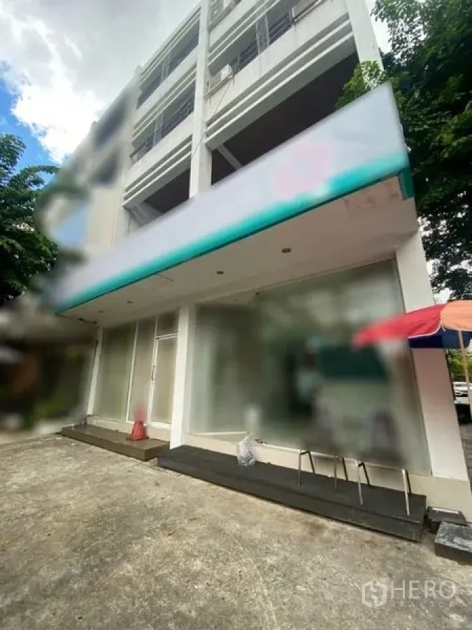 店屋 出租在Watthana, Bangkok - 四层商铺外观，宽幅玻璃门面与遮阳篷，临绿荫小巷。