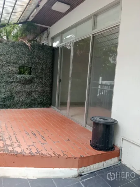 Home Office for rent in Khlong Toei, Bangkok - Front terrace with raised wooden deck, green privacy wall and sliding glass doors.