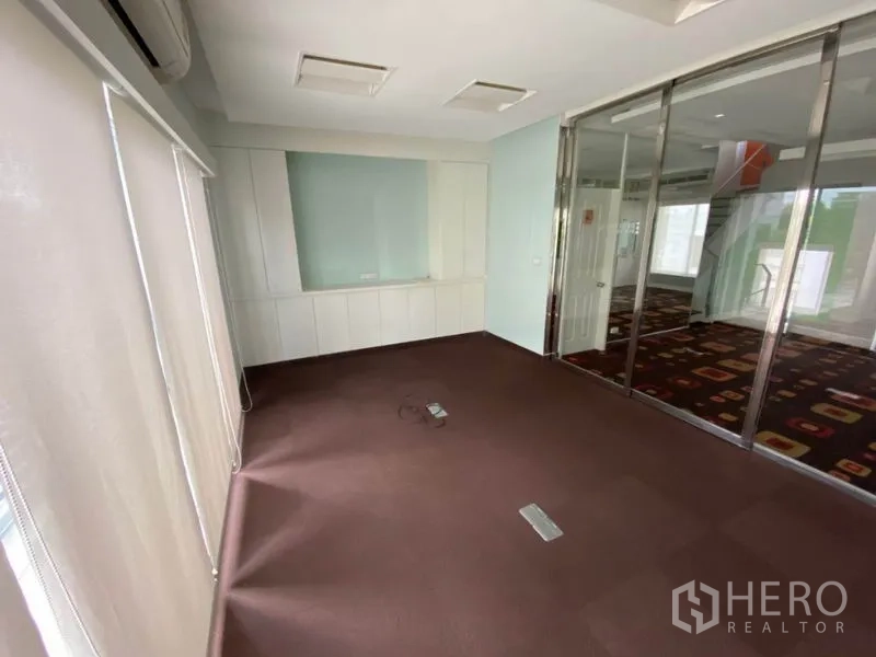 Home Office for rent in Wang Thonglang, Bangkok - Carpeted office space with glass sliding partitions, white cabinetry and blinds.