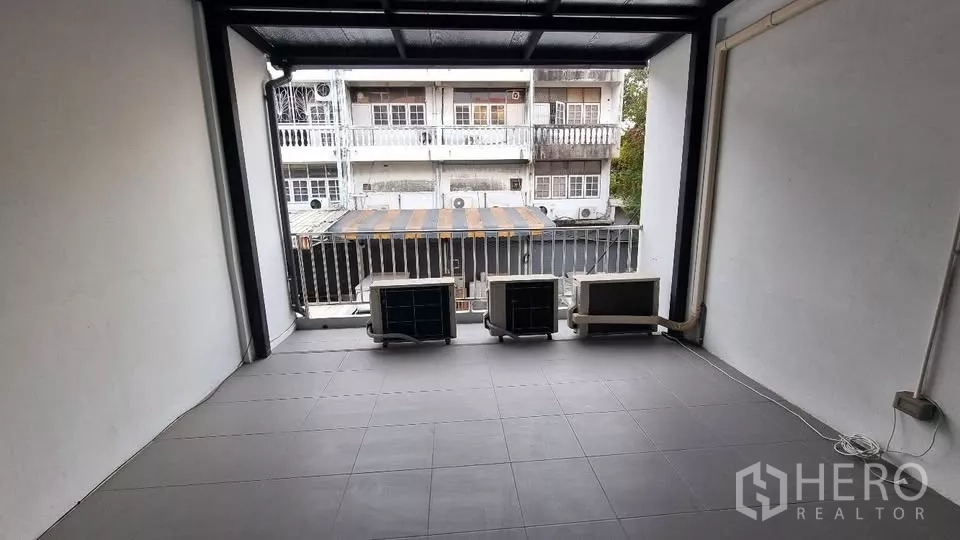 Townhouse for rent in Huai Khwang, Bangkok - Covered balcony terrace with AC compressors facing neighboring townhouses.