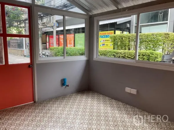 Retail Space for rent in Khlong Toei, Bangkok - Compact corner room with patterned tile floor, red door, large windows, and a plumbing point.