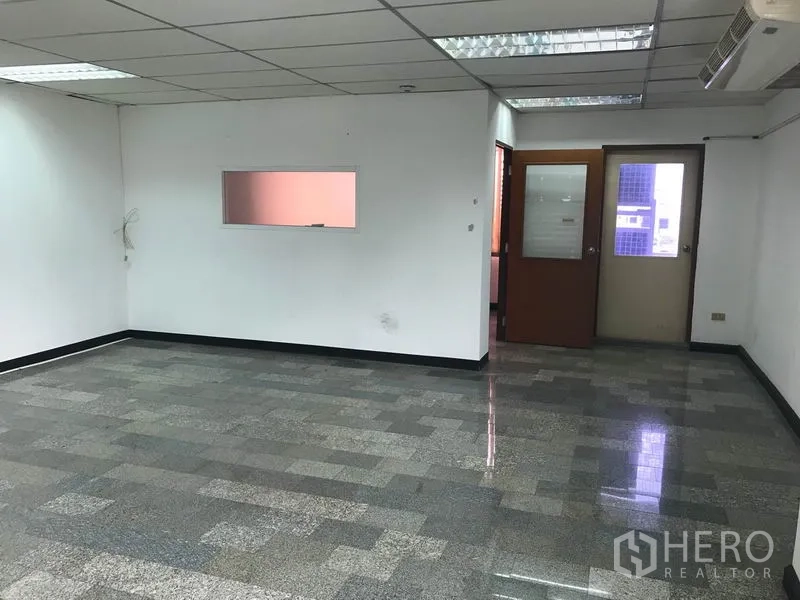 Office Space for rent in Khlong Toei, Bangkok - Spacious office floor with internal glass door, service door and a wall observation window.