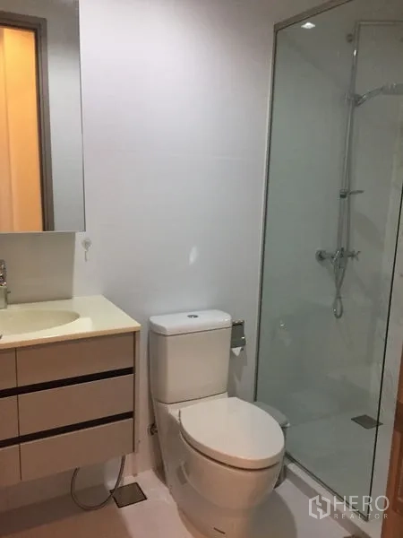 Condominium for rent in Watthana, Bangkok - Contemporary bathroom with glass shower enclosure, vanity and toilet.