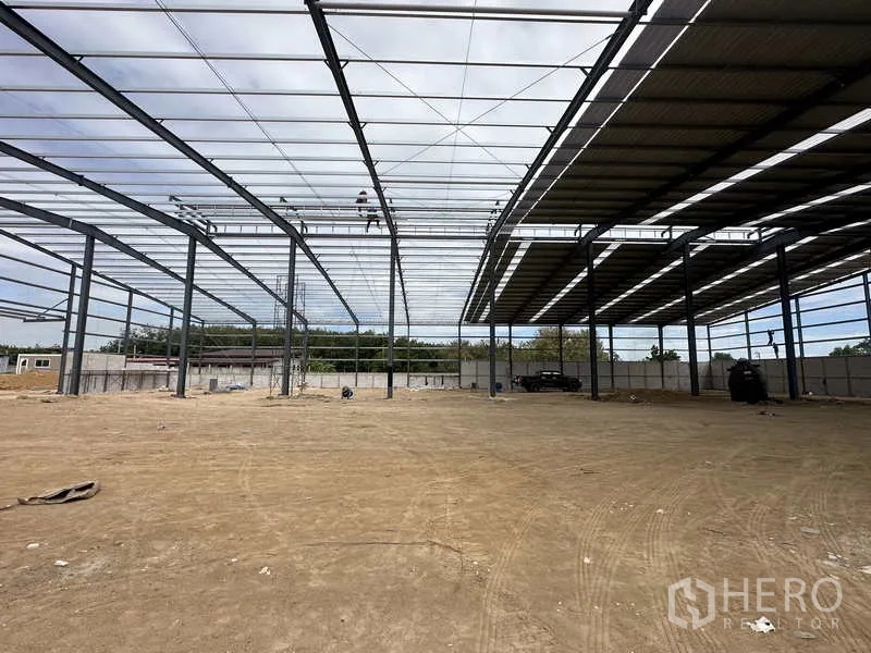 Warehouse for rent or sale in Nikhom Phatthana, Rayong - Interior of the warehouse with partial roof sheets installed and large open floor space.