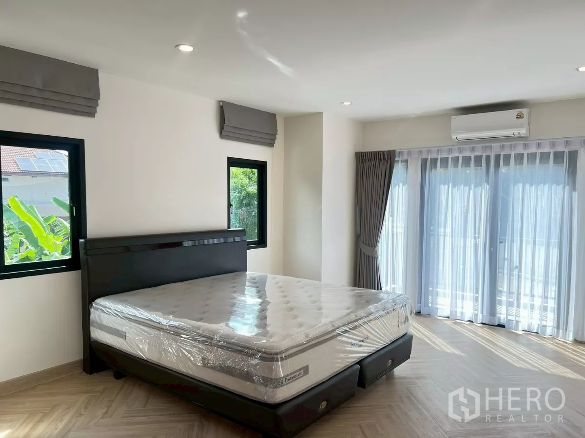 Detached House for rent in Suan Luang, Bangkok - Master bedroom detail showing large windows, curtains, and air-conditioning.