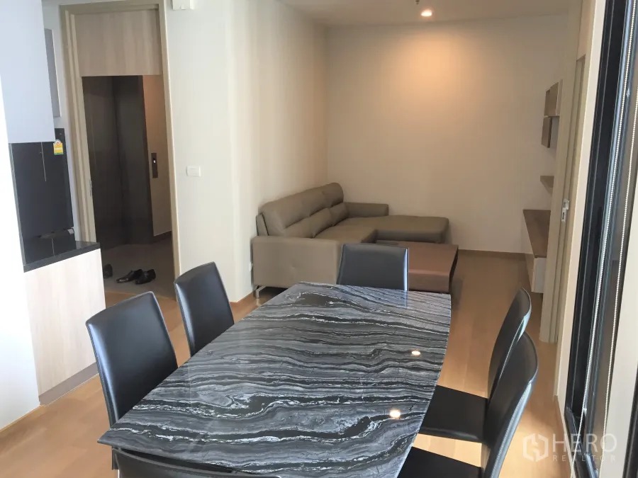 Condominium for rent in Pathum Wan, Bangkok - Open-plan dining and living area with marble-top table, leather sofa and light wood floors.