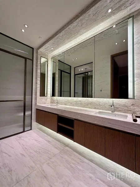 Condominium for rent or sale - Luxury bathroom with long double vanity, backlit mirrors and marble flooring.