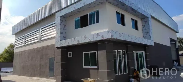 Warehouse for rent in Bang Khun Thian, Bangkok - Angled view of the warehouse showing corner office windows, louvered vents and metal roofing.
