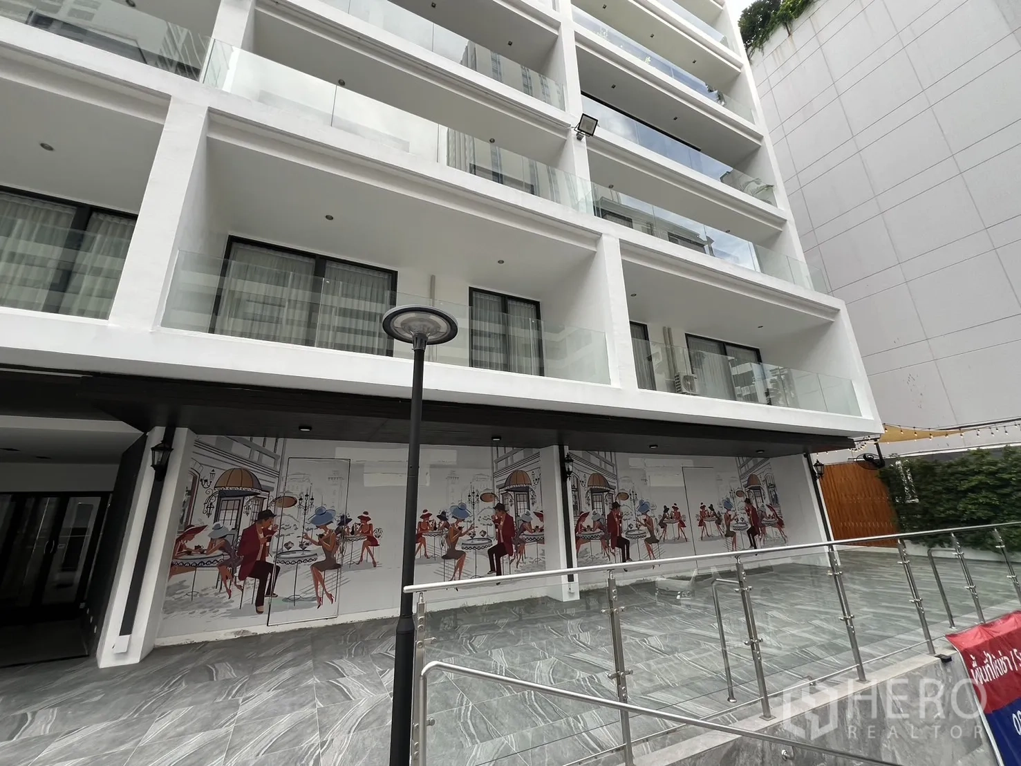 Retail Space for rent - Contemporary building facade with balconies above a retail terrace and an illustrated mural.