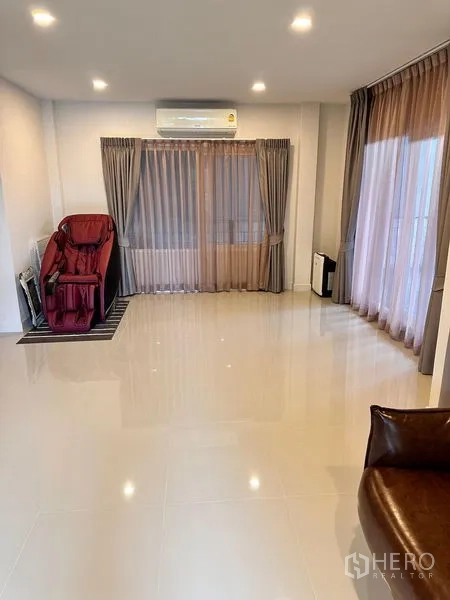 Detached House for sale in Prawet, Bangkok - Open living area with large windows, tiled floors and wall-mounted A/C.
