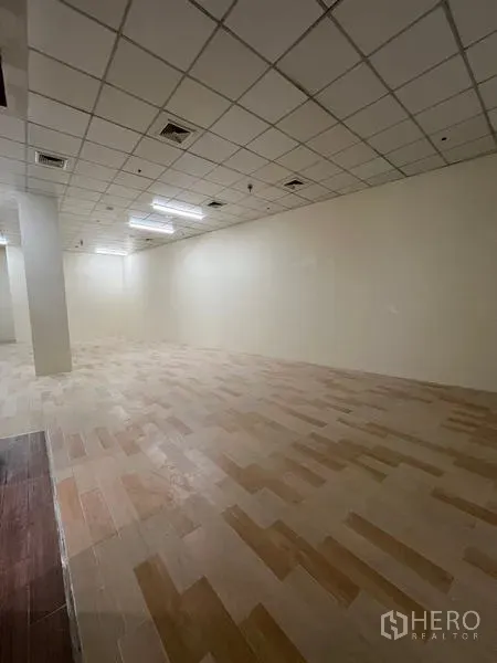 Retail Space for rent in Watthana, Bangkok - Long rectangular shop floor with suspended ceiling panels and wood-look tiles in neutral tones.