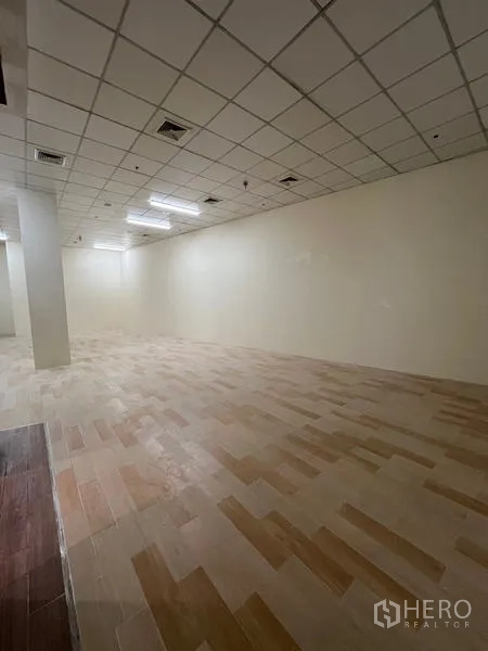 Retail Space for rent in Watthana, Bangkok - Long rectangular shop floor with suspended ceiling panels and wood-look tiles in neutral tones.