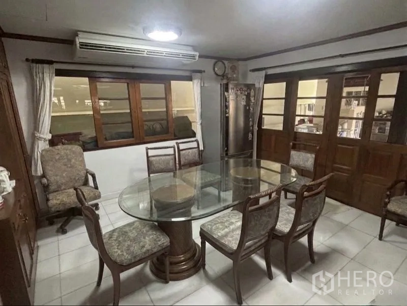 Detached House for sale in Suan Luang, Bangkok - Dining room with round glass table, six chairs and wooden sliding doors.