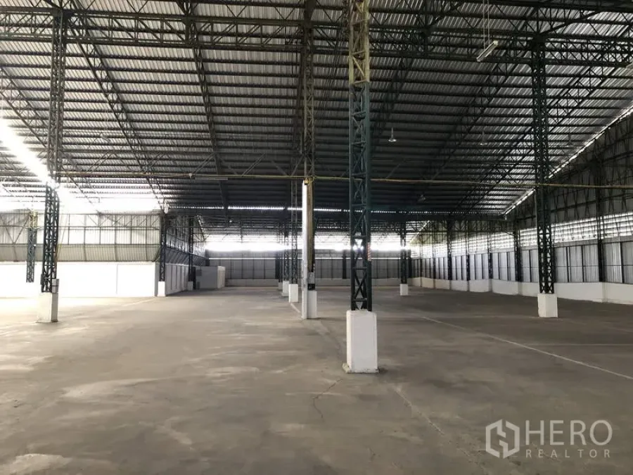 Warehouse for rent in Mueang Pathum Thani, Pathum Thani - Large warehouse interior in Mueang Pathum Thani with high steel truss roof, wide column span and smooth concrete floor.