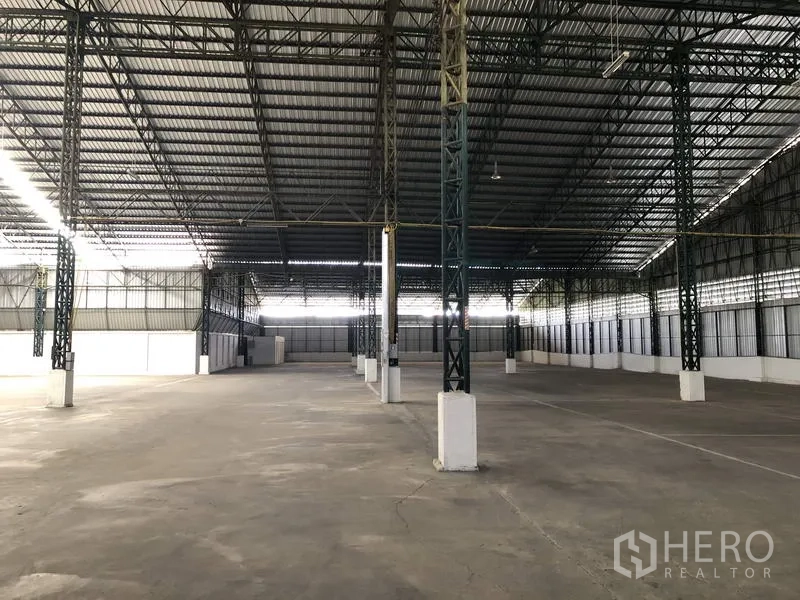 Warehouse for rent in Mueang Pathum Thani, Pathum Thani - Large warehouse interior in Mueang Pathum Thani with high steel truss roof, wide column span and smooth concrete floor.