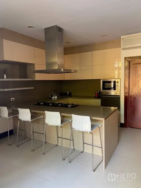 Detached House for rent in Suan Luang, Bangkok - Modern kitchen with island breakfast bar, gas cooktop, range hood and bar stools.