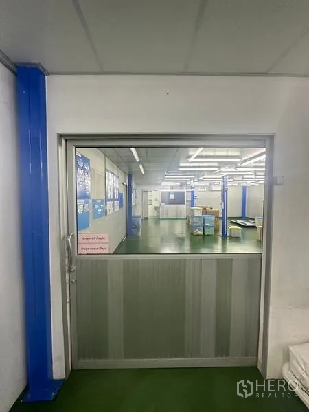 Warehouse for rent or sale in Lam Luk Ka, Pathum Thani - Sliding door entrance to a clean production hall with bright lighting.