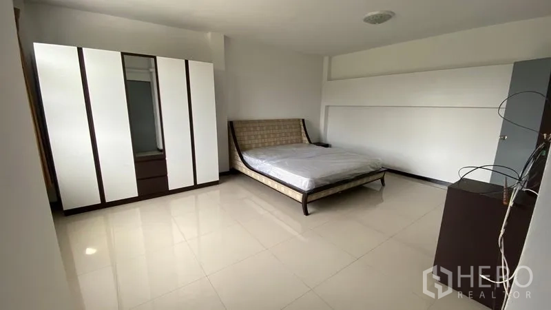Townhouse for rent in Bang Na, Bangkok - Bedroom view showing bed, wardrobe and neutral tile flooring.