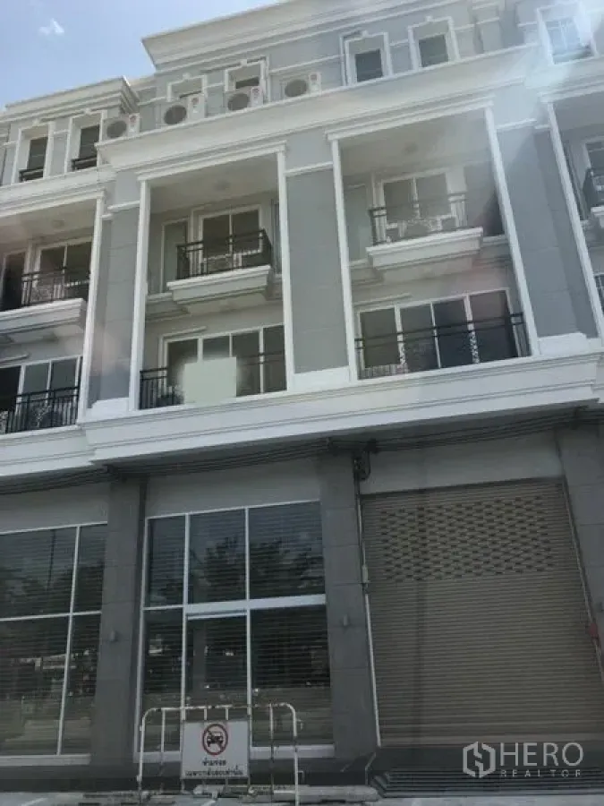 Shophouse for rent in Bang Na, Bangkok - Modern multi-storey shophouse facade with glass storefront, balconies and a roller shutter in Bang Na.