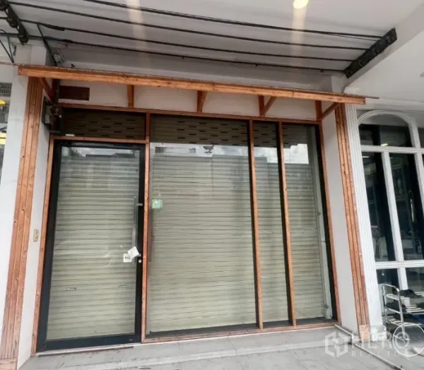 Shophouse for rent - Ground-floor storefront with glass entry door, metal roller shutters, and a wooden awning.