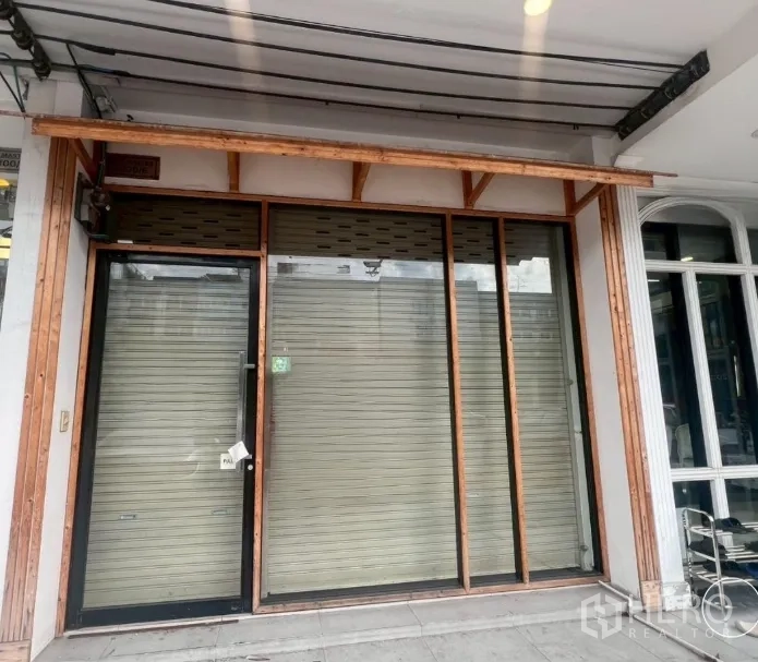 Shophouse for rent - Ground-floor storefront with glass entry door, metal roller shutters, and a wooden awning.