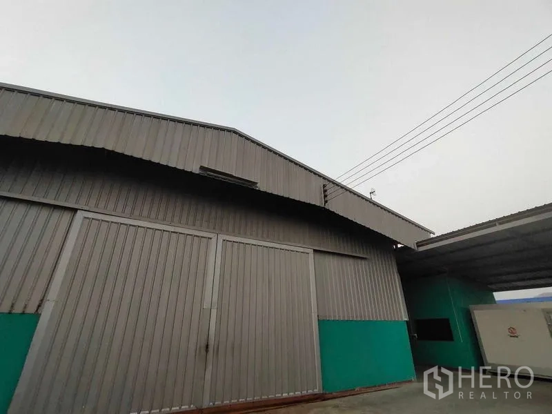 Warehouse for sale in Lam Luk Ka, Pathum Thani - Close-up of the warehouse facade showing large metal sliding doors and wide eaves.