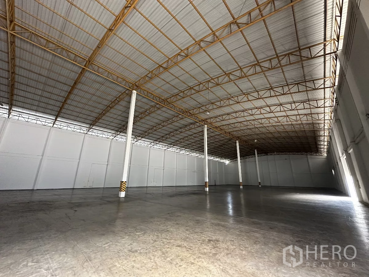 Warehouse for rent in Phra Nakhon Si Ayutthaya - Spacious warehouse interior featuring a high arched steel roof, white walls, and polished concrete floor.