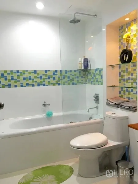 Condominium for rent in Pathum Wan, Bangkok - Bathroom with bathtub, glass shower screen, rain shower, toilet, and mosaic accent tiles.