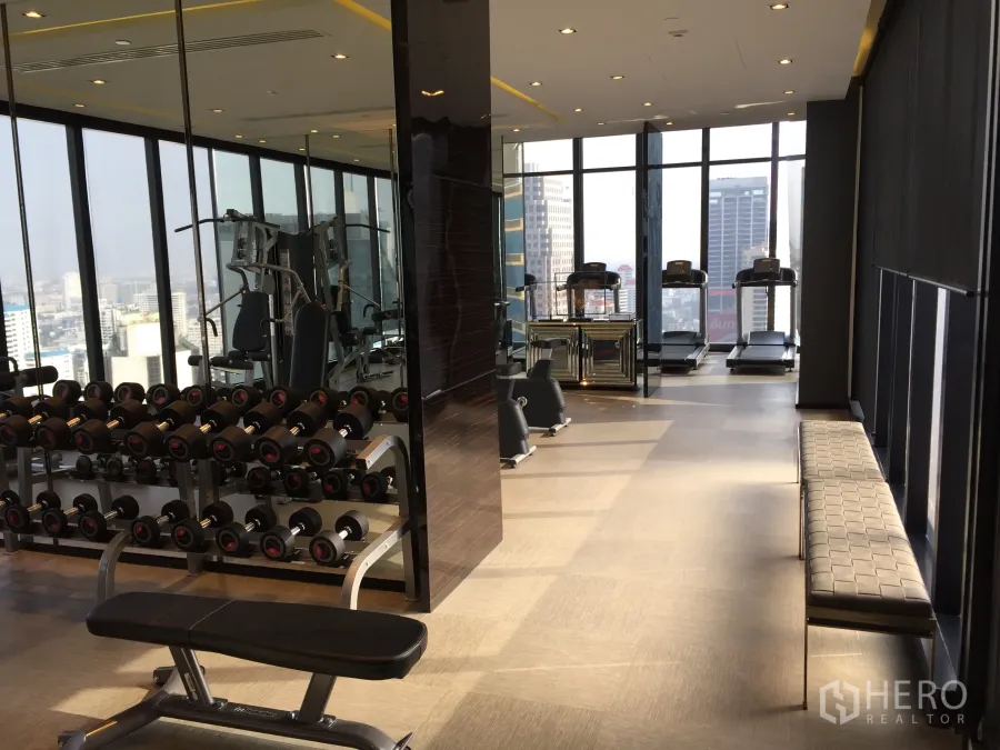 Condominium for sale in Watthana, Bangkok - Skyline-view fitness center with treadmills, free weights and floor-to-ceiling windows.